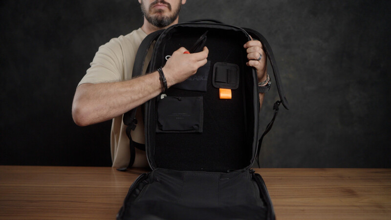 Man opening a black camera backpack to display its interior organization and storage compartments