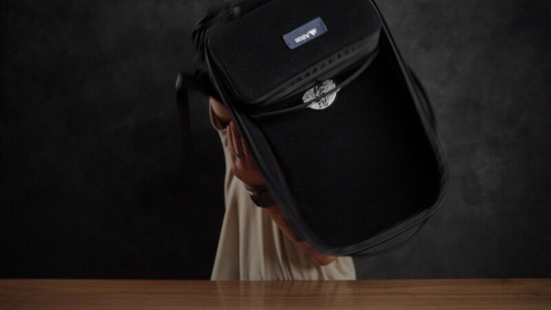 Black camera bag with Harley-Davidson logo on wooden table against dark background