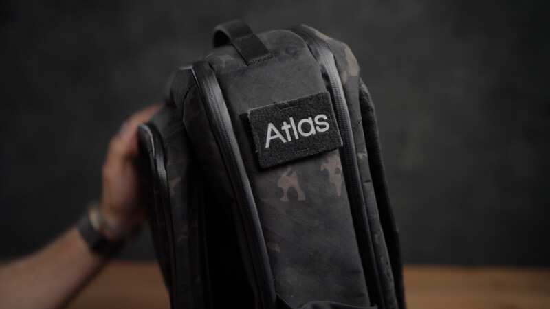 Black Atlas camera bag held in hand against dark background