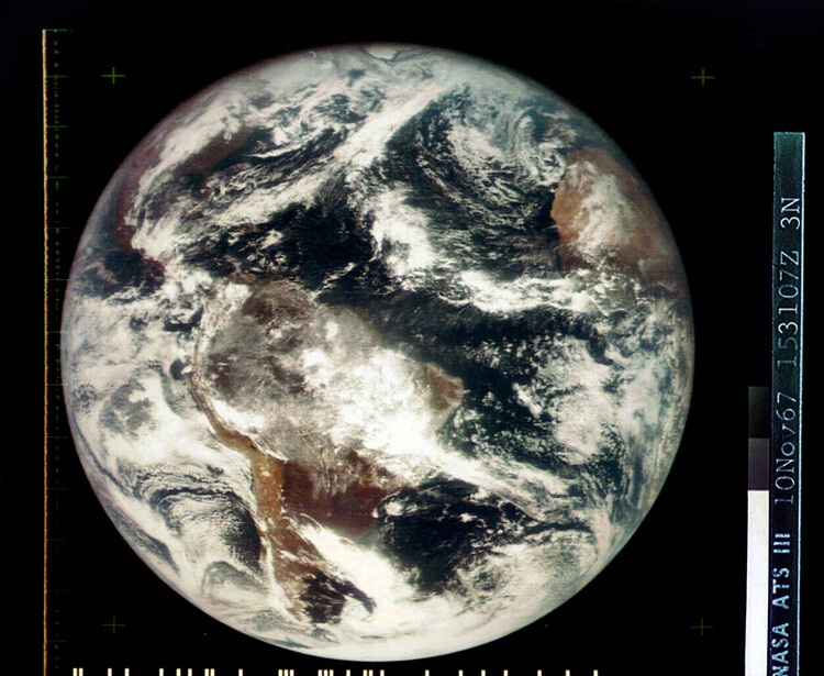 Satellite photograph of Earth showing cloud formations, continents, and atmospheric patterns against black space