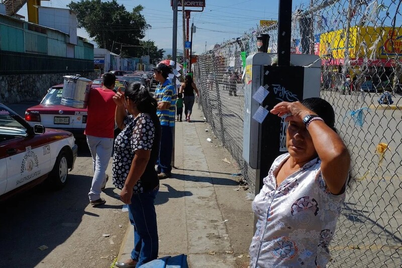 Woman in white shirt shields eyes from bright sunlight on urban street