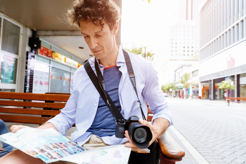 Photographer with curly red hair holding camera while reviewing contact sheet outdoors