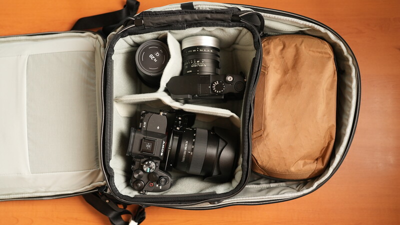 Camera bag organizer displaying medium format camera, telephoto lens, and accessories against orange background