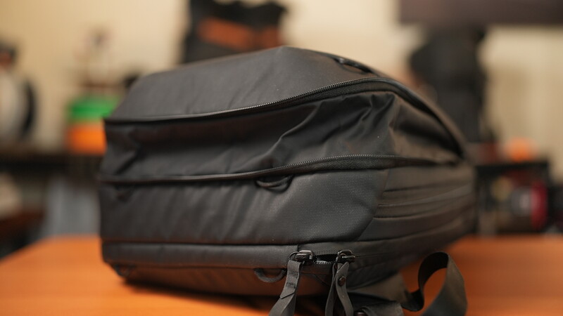 Black camera backpack with multiple compartments displayed on orange surface
