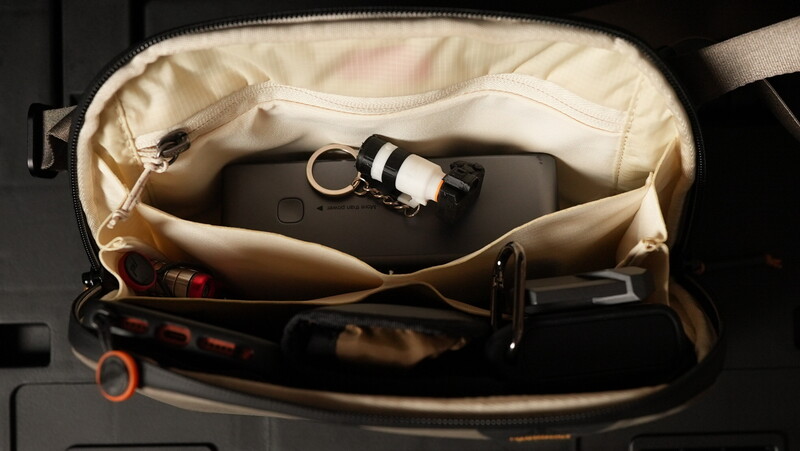 Open camera bag with organized compartments displaying a mirrorless camera body and accessories