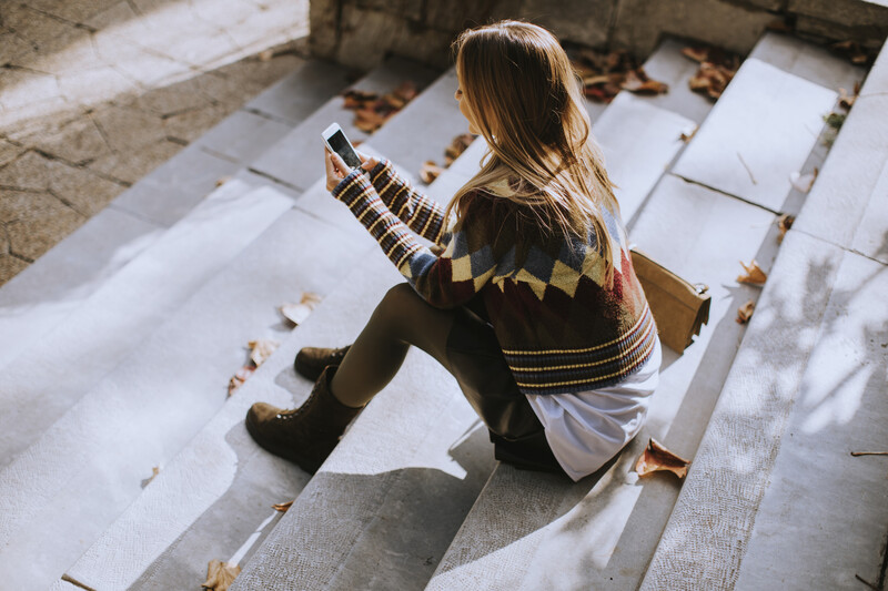 Child sitting on white wooden deck, viewed from above, holding a camera
