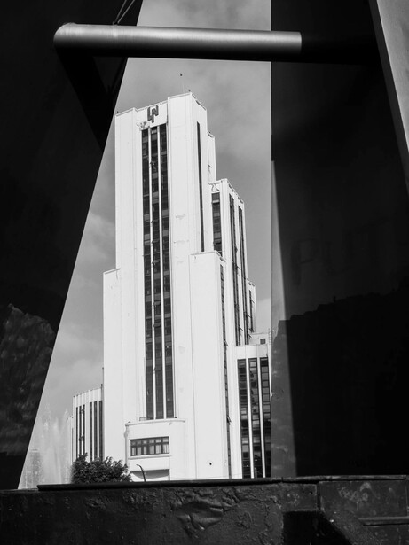 Art Deco skyscraper photographed from below through geometric framing, black and white