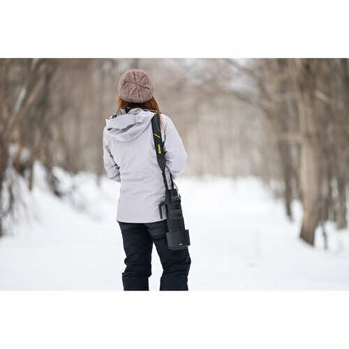 Woman jogging on snowy tree-lined path wearing white puffer jacket and beanie