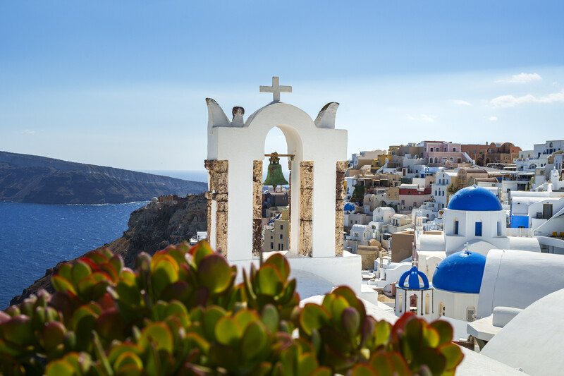 White chapel with blue dome and cross overlooking Aegean Sea in Santorini