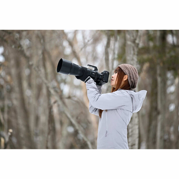 Photographer with telephoto lens capturing wildlife in winter forest