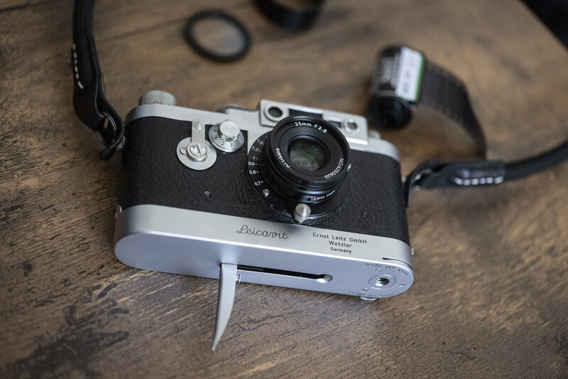 Vintage rangefinder camera with black leather body and chrome top plate on wooden surface