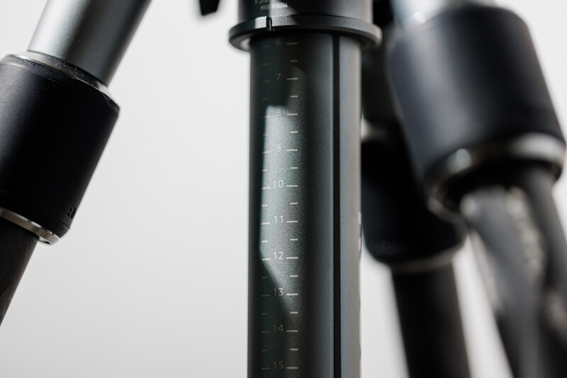 Close-up of a camera tripod center column with measurement markings and adjustment handles
