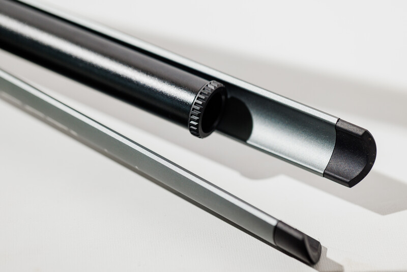 Two lens filters or optical tubes arranged diagonally on white surface with hard shadows