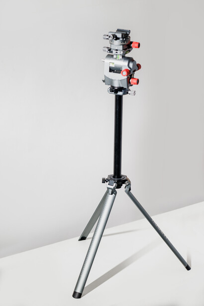 Compact camera rig with three red-accented cameras mounted vertically on adjustable arms, attached to a black tripod stand