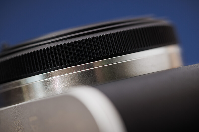 Close-up macro shot of camera lens filter ring and threading against blue background