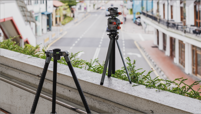 Two black tripods positioned on a concrete ledge overlooking an urban street