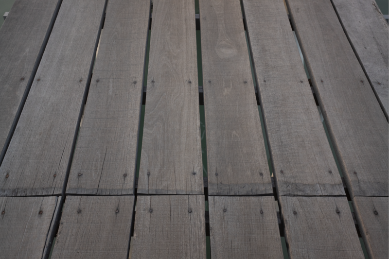 Overhead view of weathered wooden deck boards with linear grain patterns and knots