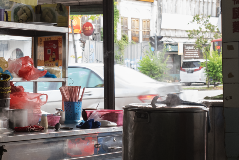 Shop window display with red kitchenware and decorative items reflecting street scene