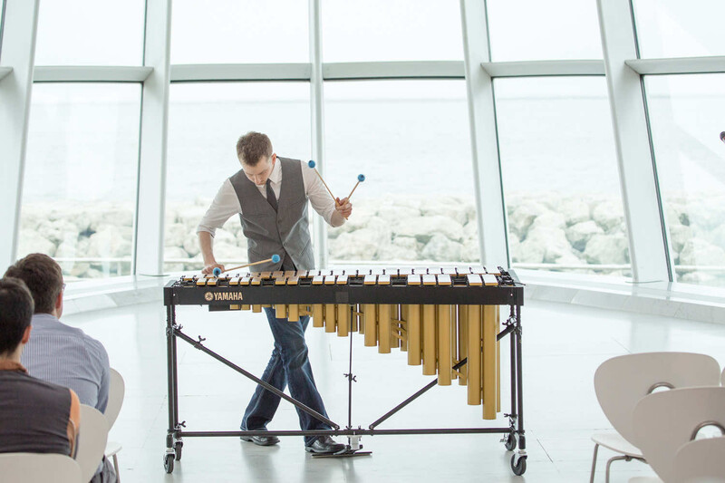 Musician playing vibraphone in high-rise studio with floor-to-ceiling windows overlooking cityscape