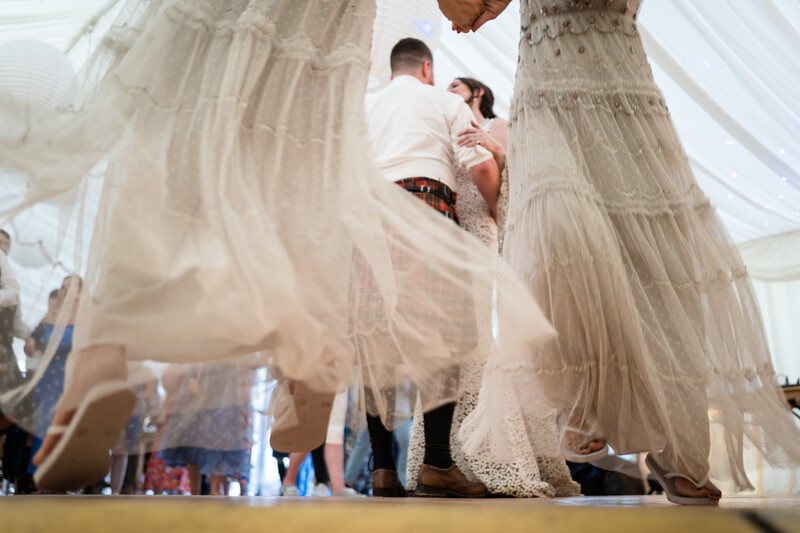 Bride in tiered tulle gown viewed from below, groom in white shirt adjusting her dress during wedding preparation
