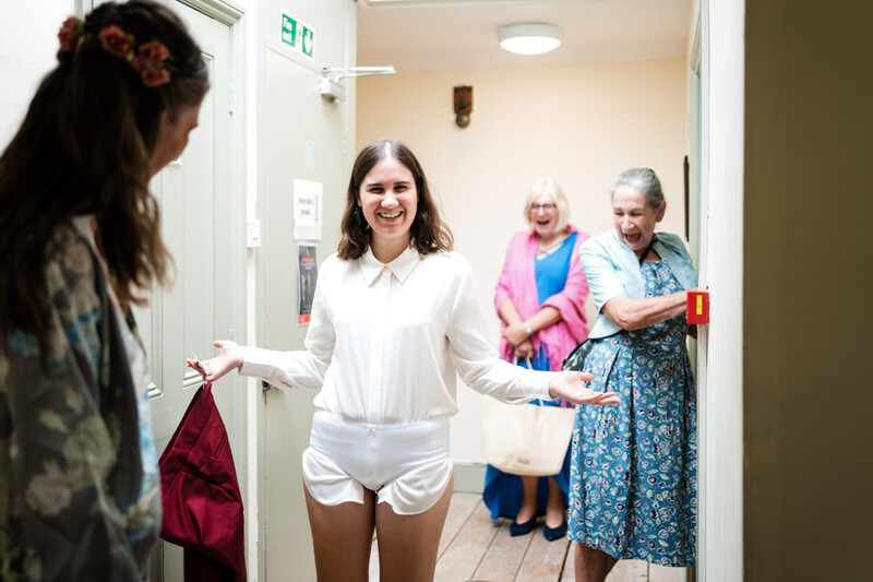 Young woman in white shirt posing in doorway while others watch behind her