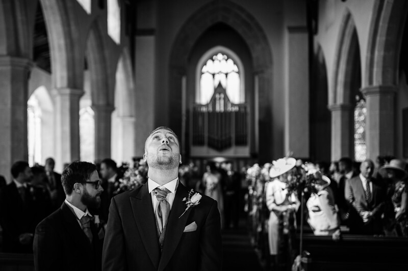 Groom looking upward in Gothic cathedral during wedding ceremony, black and white