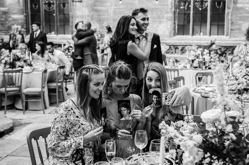 Black and white wedding reception scene with guests toasting at an outdoor venue