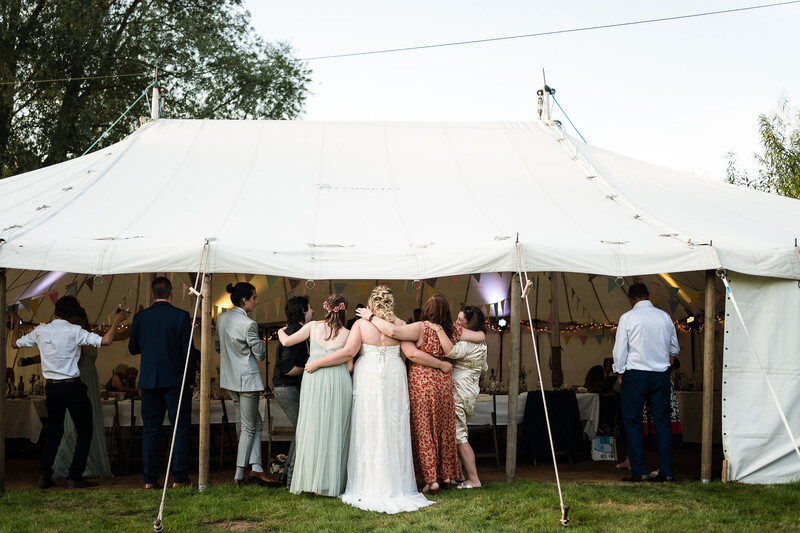 Wedding guests gathered under a large white tent during an outdoor reception