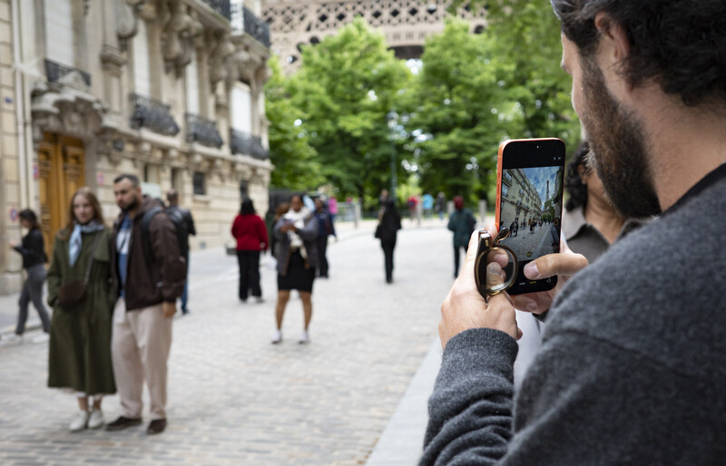 Man photographing a Parisian street scene with a smartphone