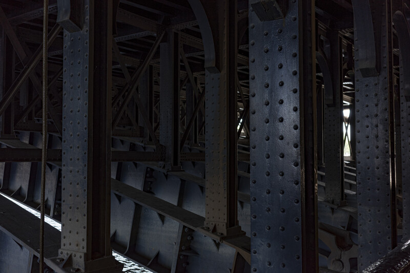 Underneath view of steel bridge infrastructure with riveted metal beams and structural framework