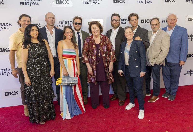 Group of twelve people posing together on a red carpet in front of a Tribeca Film Festival backdrop