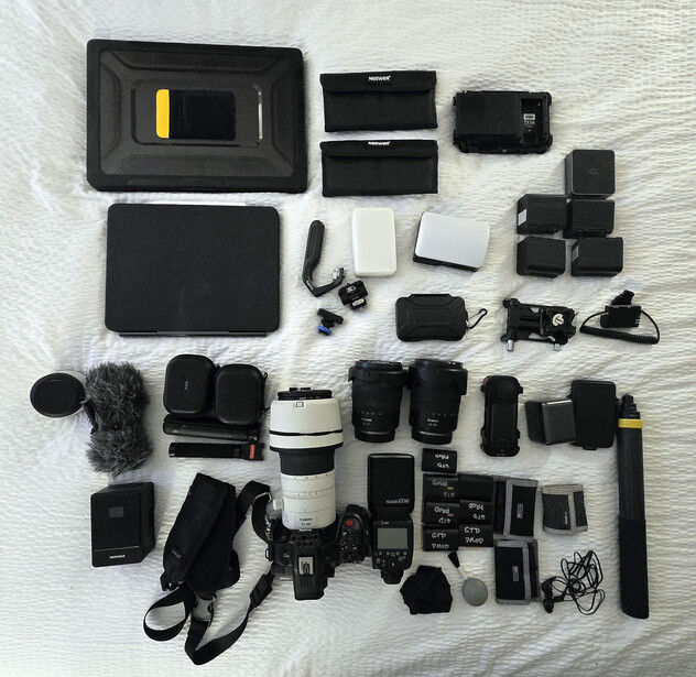Flat lay of professional video and audio production equipment including cameras, lenses, microphones, lighting, and accessories