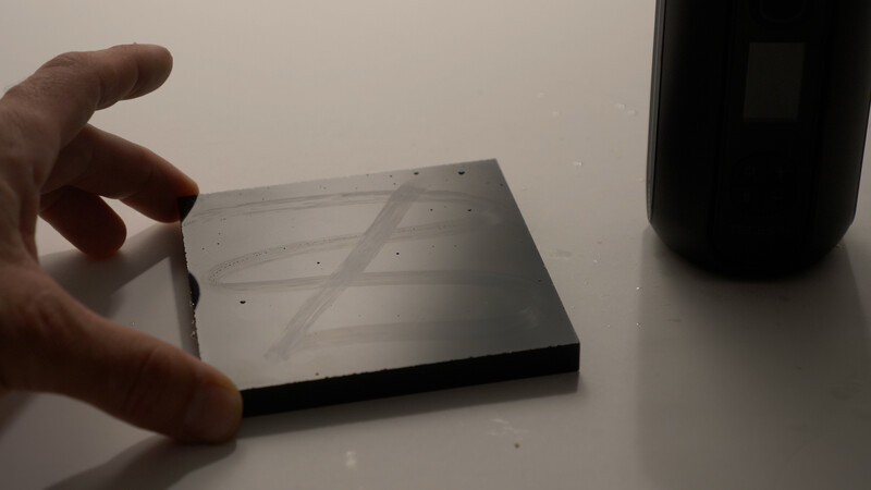 Hand holding a translucent acrylic sheet with diffusion patterns and small holes against a white surface