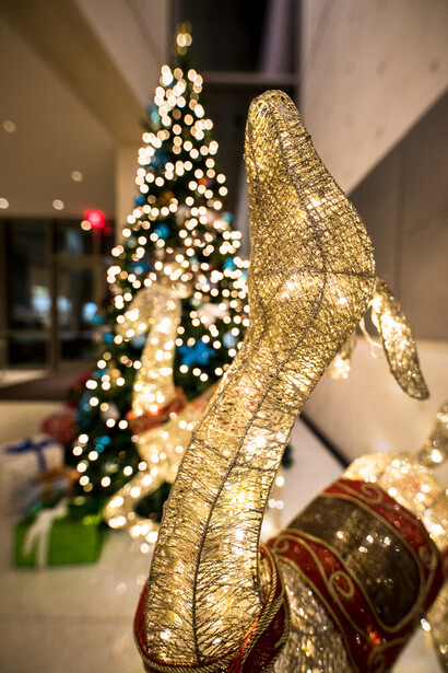 Gold textured reindeer figurine with Christmas tree and ornaments in soft-focus background
