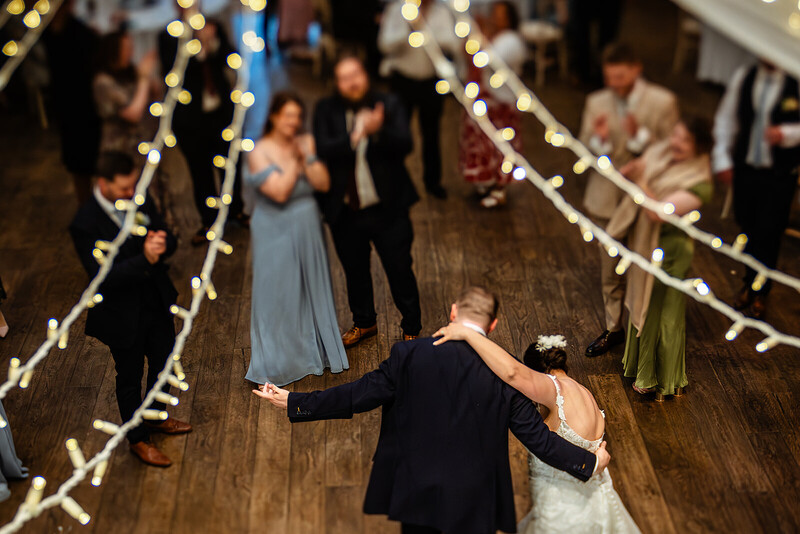 Bride and groom first dance under string lights at wedding reception