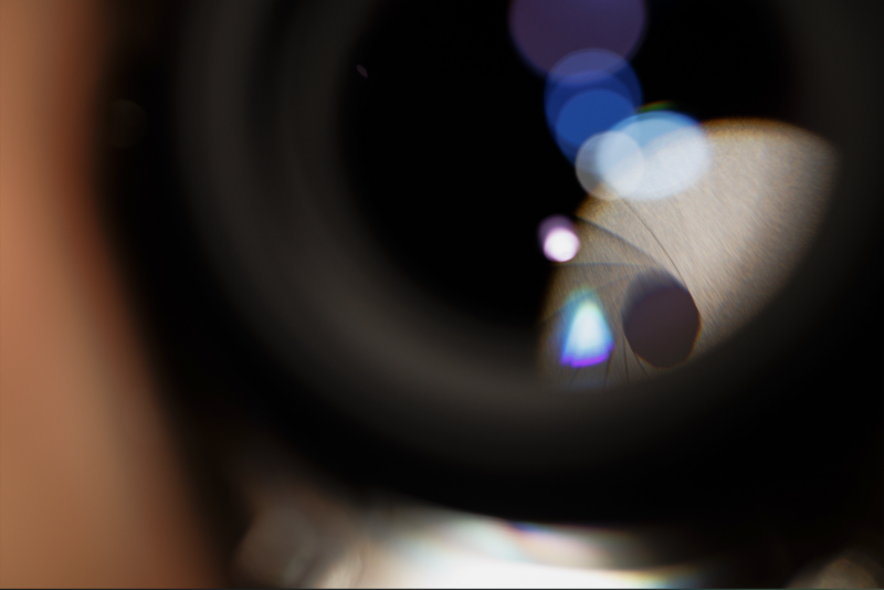 Macro photography of a camera lens with bokeh lights in background