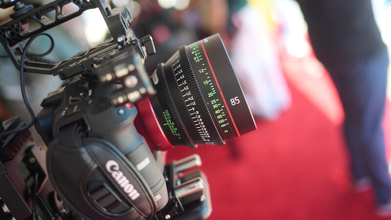 Canon cinema camera with Samyang cine lens mounted, shot at shallow depth of field with red carpet event background