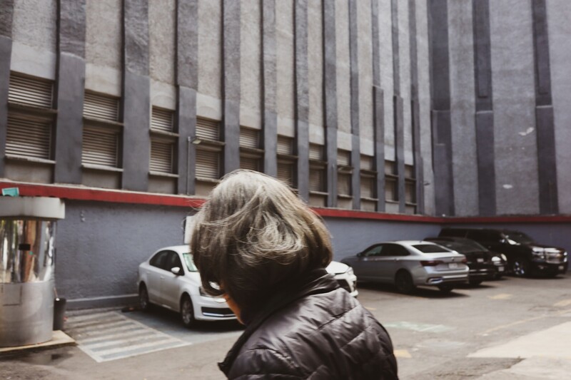 Person with blonde hair photographing parked cars in a concrete parking garage