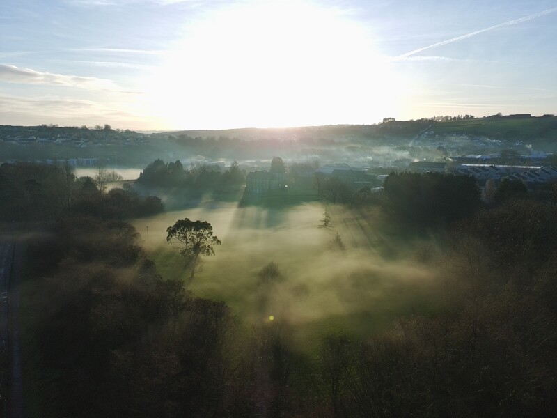 Misty valley landscape at sunrise with forested hills and distant water