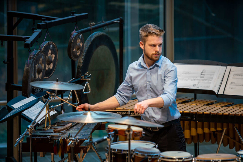 Musician playing vibraphone in studio with drums and keyboards visible