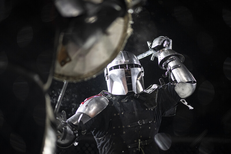 Action figure of armored warrior in dynamic pose against dark background with blurred spacecraft