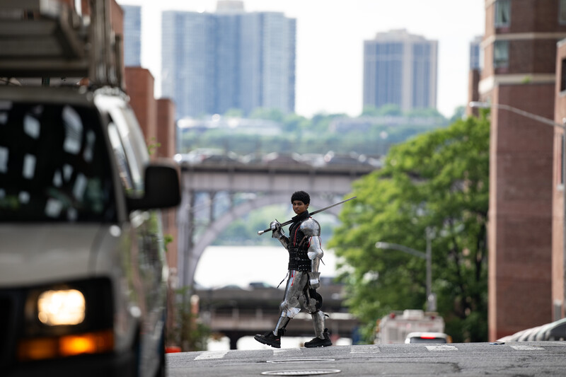 Urban cyclist riding through city street with selective focus, blurred truck and skyscrapers in background