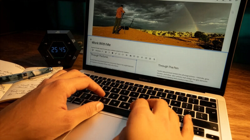 Photographer's hands typing on MacBook displaying landscape photography workflow