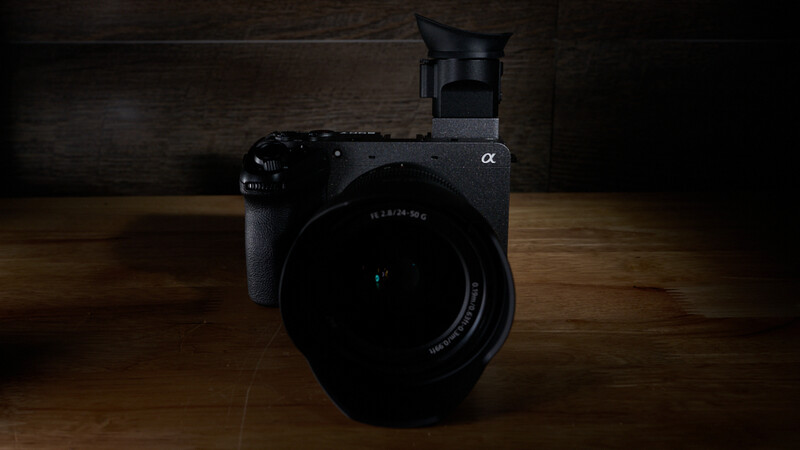 Sony Alpha mirrorless camera with lens and external flash on wooden surface