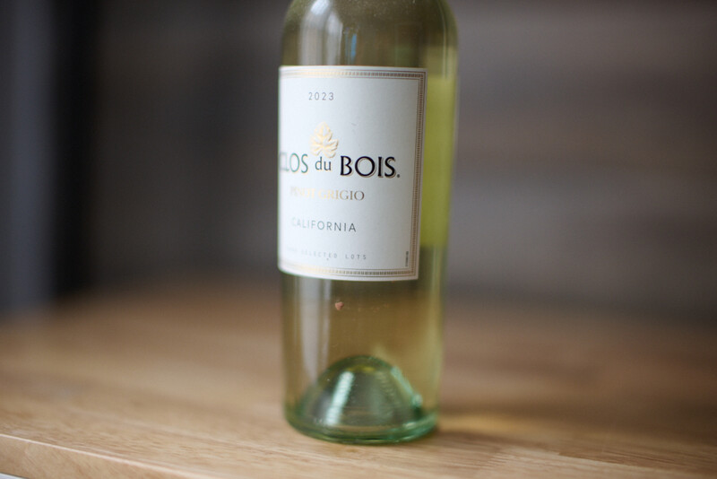 Bottle of Dos du Bois white wine from California with pale yellow liquid and white label on wooden surface