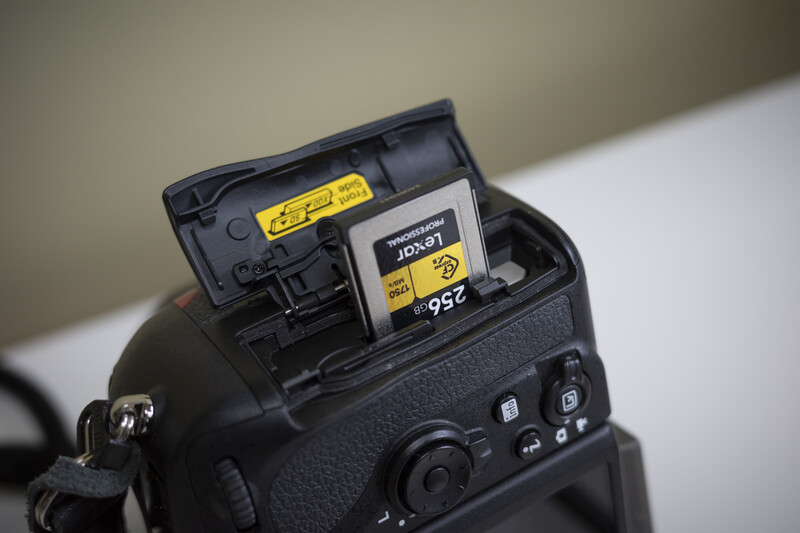 DSLR camera with open SD card slot revealing a Sandisk Extreme CompactFlash memory card