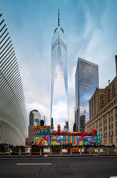One World Trade Center rising between modern skyscrapers and a colorful street installation in lower Manhattan