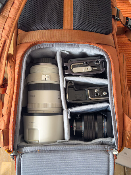 Orange camera backpack with organized lens and equipment compartments displayed open