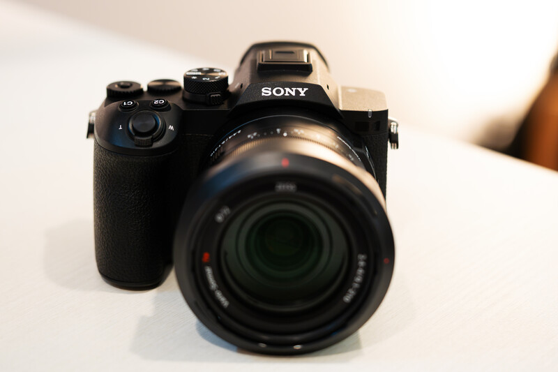 Sony mirrorless camera with attached zoom lens on white surface