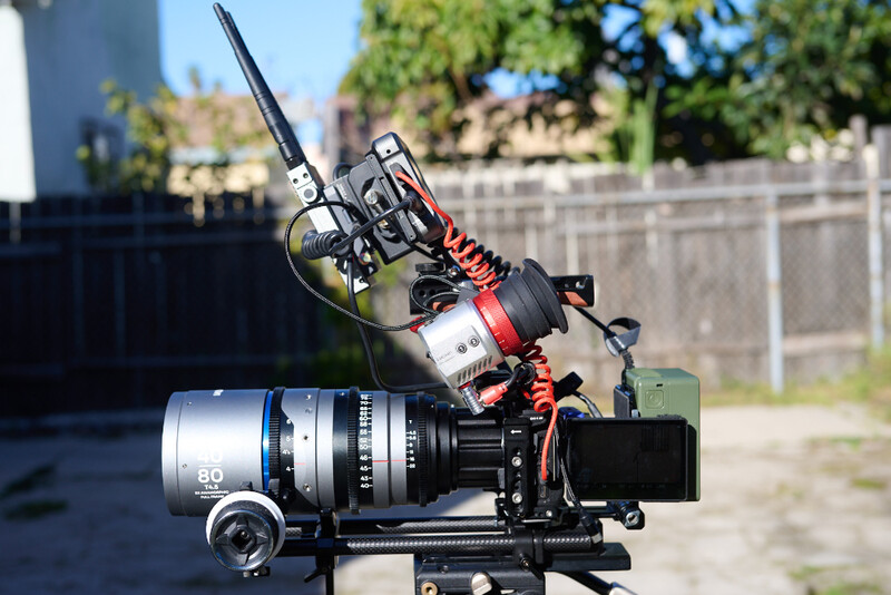 Professional cinema camera rig with telephoto lens, microphone, and monitor mounted on support bracket